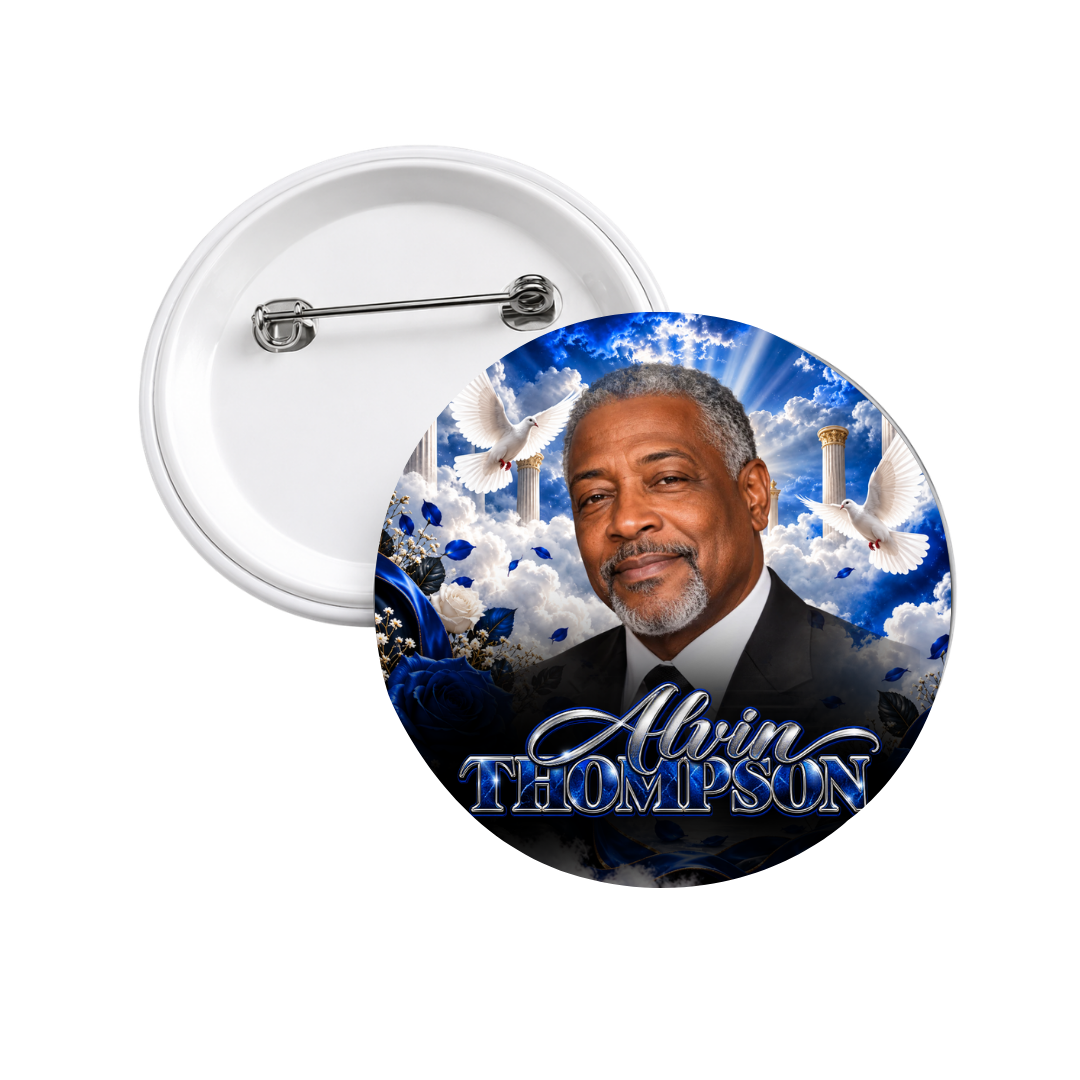 Custom memorial photo button with a portrait of a smiling man in a dark suit, framed by heavenly clouds, white doves, golden pillars, and blue roses, with a name in silver script. The pin back is shown behind it.