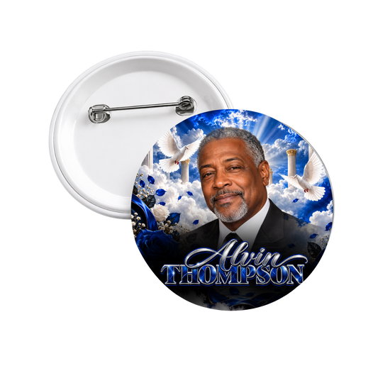 Custom memorial photo button with a portrait of a smiling man in a dark suit, framed by heavenly clouds, white doves, golden pillars, and blue roses, with a name in silver script. The pin back is shown behind it.